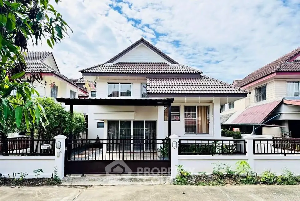 Charming two-story house with tiled roof and gated front yard in a serene neighborhood.
