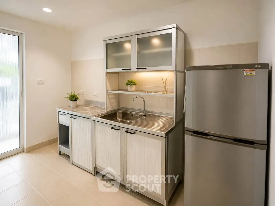 Modern kitchen with sleek cabinets and stainless steel fridge in a bright apartment.