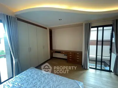 Spacious bedroom with large windows and built-in wardrobe, featuring elegant lighting and hardwood floors.