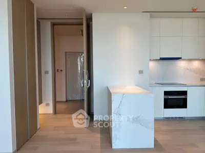 Modern kitchen with sleek white cabinetry and marble island in luxury apartment.