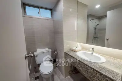 Modern bathroom with sleek design, featuring a granite countertop and spacious shower area.