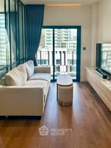 Modern living room with large window and city view, featuring a cozy sofa and sleek wooden flooring.