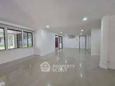 Spacious modern living room with large windows and polished tile flooring