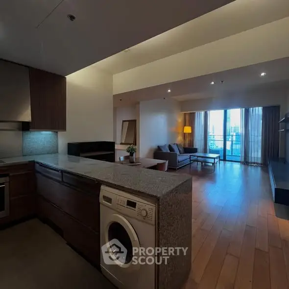 Spacious open-plan living room with modern kitchen and balcony view.