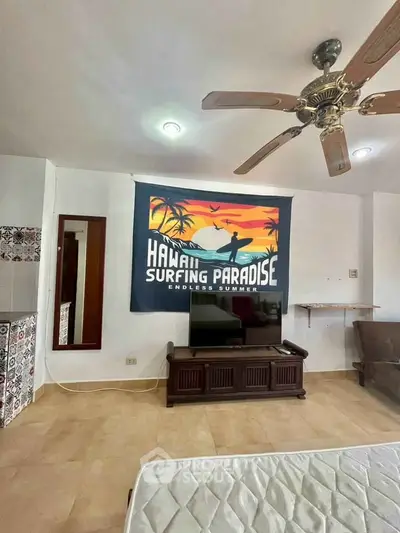 Spacious living room with ceiling fan and surfing-themed decor, perfect for relaxation.