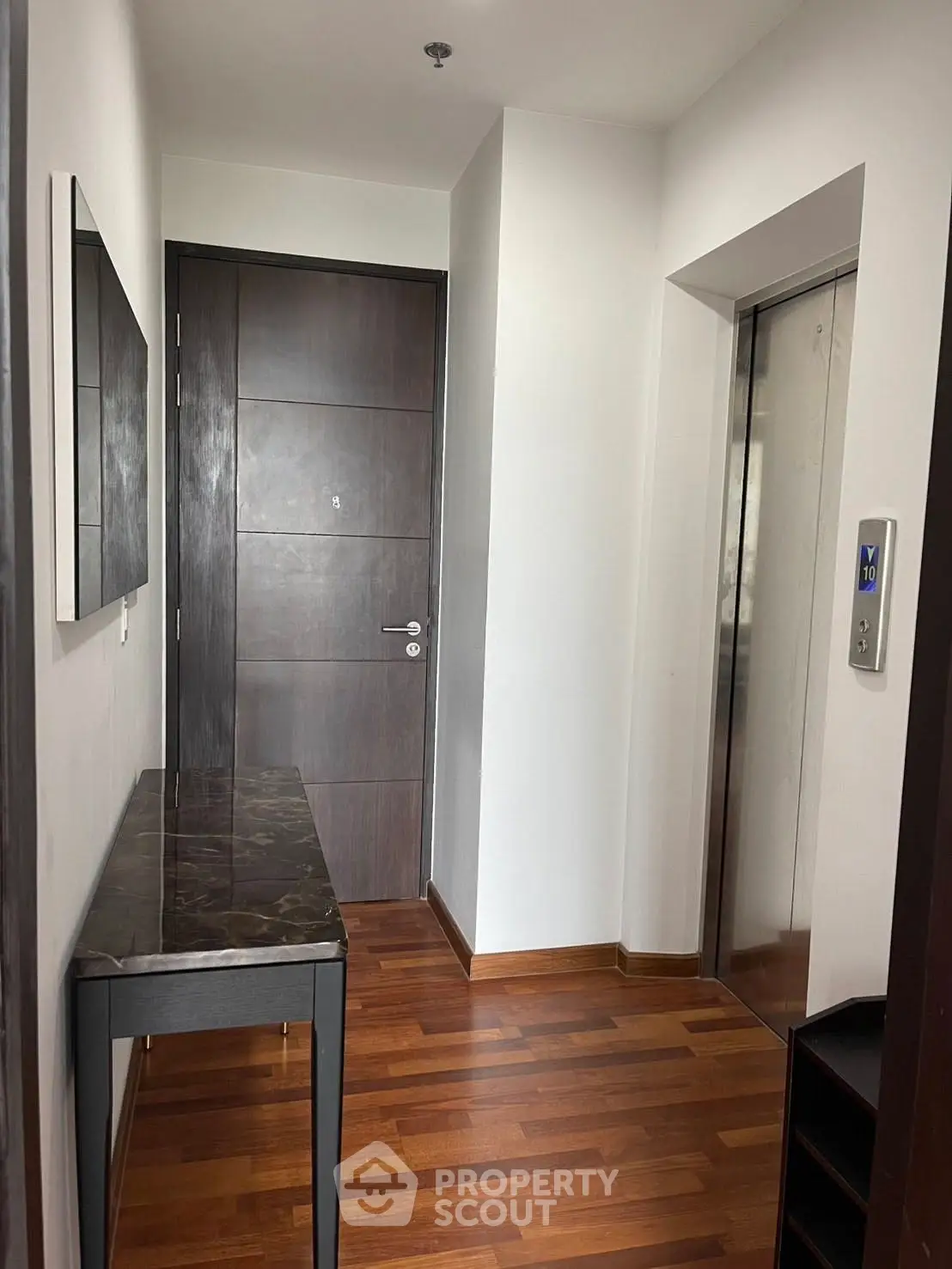 Modern apartment entrance with sleek elevator and wooden flooring