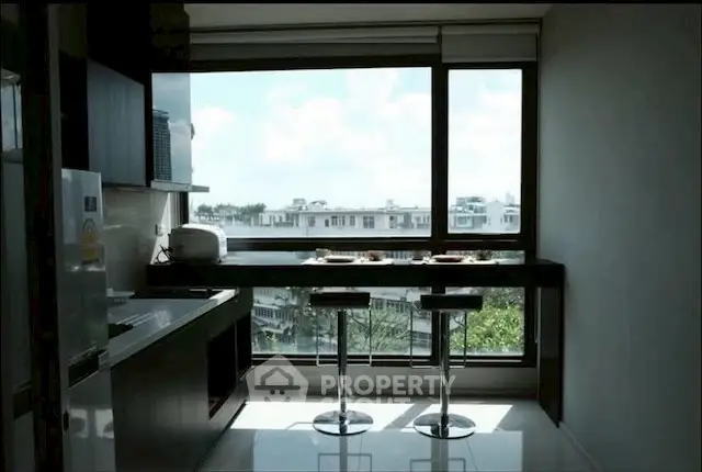 Modern kitchen with large window and scenic view, featuring sleek bar stools and contemporary design.