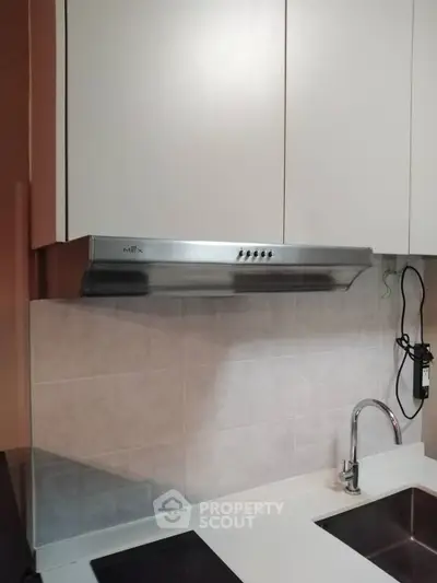 Modern kitchen with sleek stainless steel range hood and white cabinetry