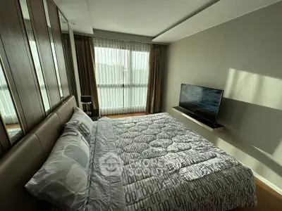 Modern bedroom with stylish decor and wall-mounted TV in a bright apartment.