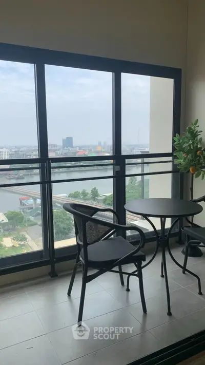 Stunning balcony view with modern furniture overlooking a serene river and cityscape.
