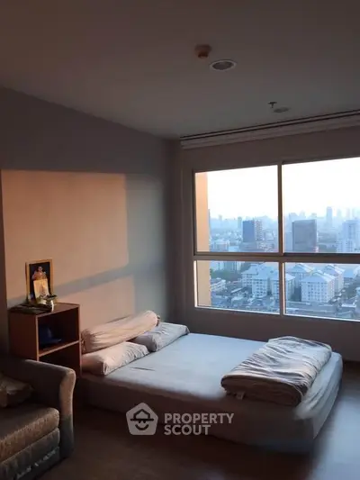 Cozy bedroom with stunning city view and natural light, featuring a minimalist bed setup.