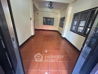 Spacious tiled room with large windows and sliding doors, perfect for versatile use.