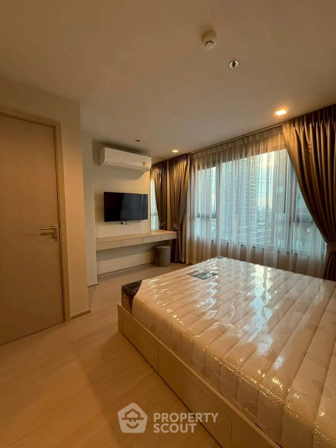 Modern bedroom with large window and natural light in urban apartment.