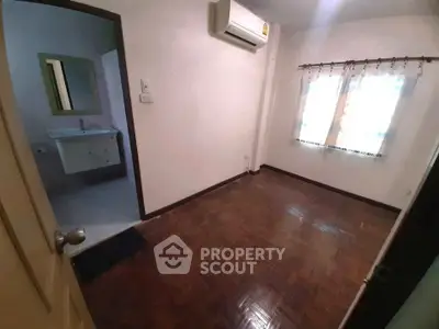 Cozy bedroom with parquet flooring and air conditioning, adjacent to a modern bathroom.