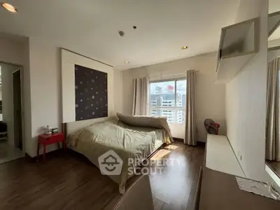 Spacious bedroom with city view, modern decor, and natural light in a high-rise apartment.