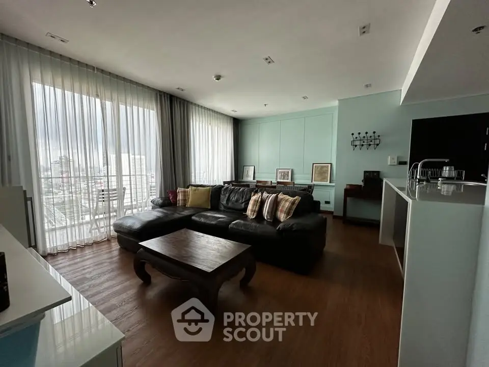Spacious living room with large windows and modern decor in a high-rise apartment.