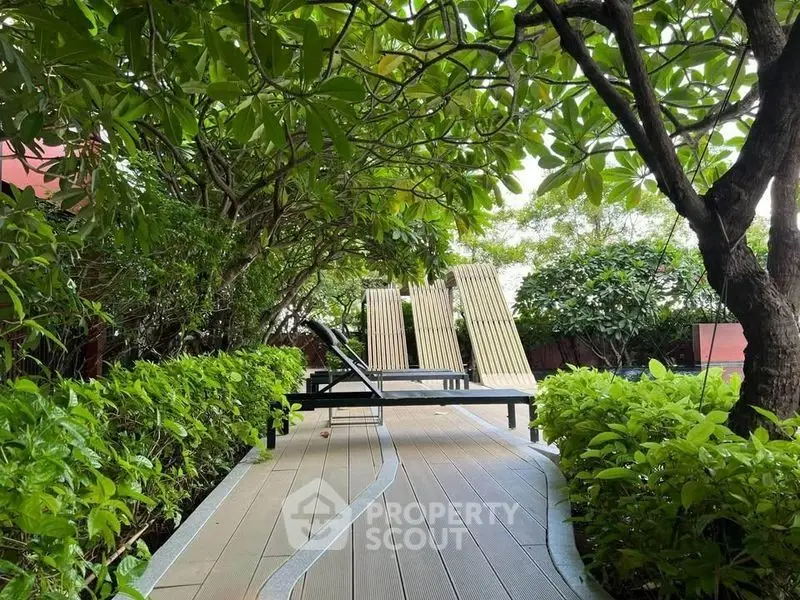 Serene garden path with lounge chairs surrounded by lush greenery
