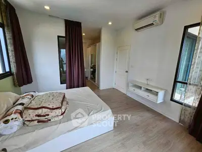 Spacious bedroom with modern decor and air conditioning, featuring large windows and wooden flooring.
