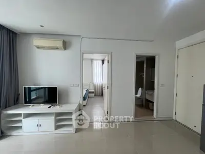 Modern apartment interior with TV, air conditioning, and view into bedroom and bathroom.