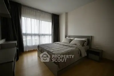 Modern bedroom with large window and stylish decor in a contemporary apartment.