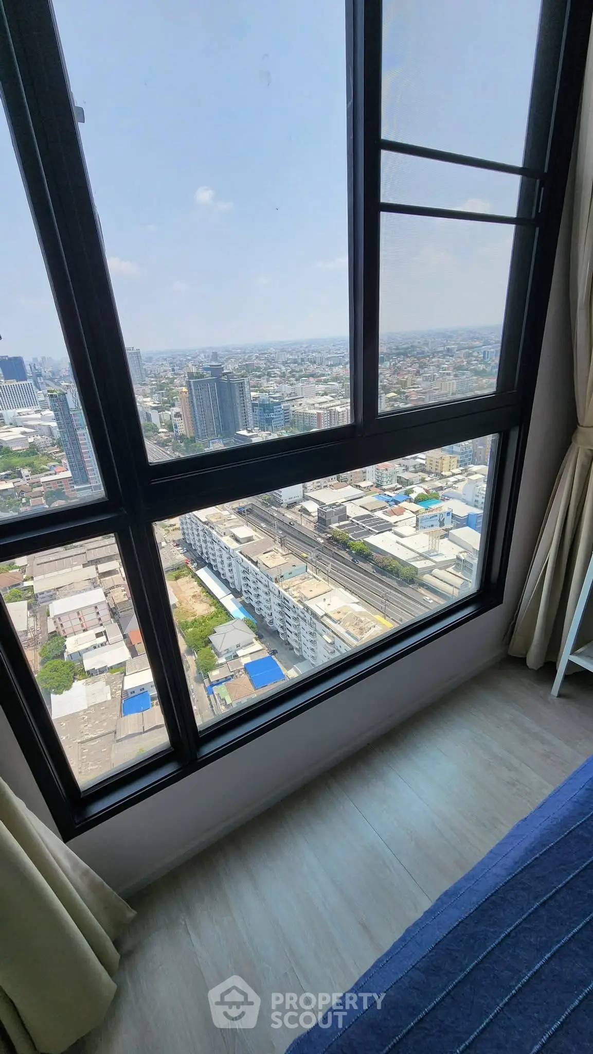 Stunning high-rise city view from a modern apartment window, showcasing urban skyline and bright daylight.