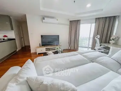 Spacious living room with modern decor and large windows offering natural light and a view.