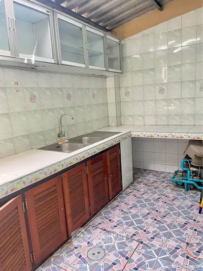 Charming kitchen with tiled walls and unique floor pattern, featuring ample storage and a stainless steel sink.