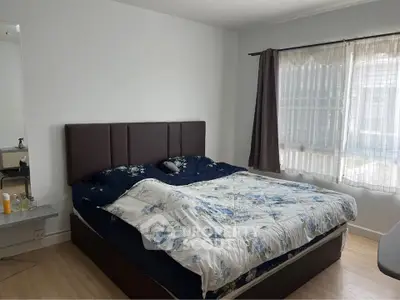 Cozy bedroom with large bed and natural light from window, perfect for relaxation.