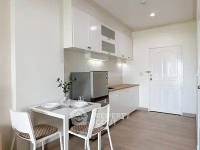 Modern kitchen with sleek white cabinets and compact dining area in a cozy apartment.
