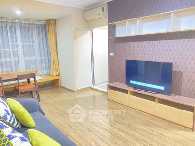 Modern living room with stylish decor and large TV in a cozy apartment.