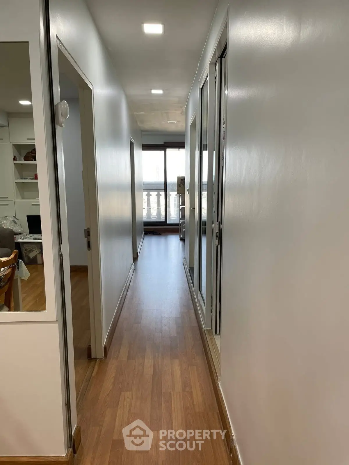 Bright hallway with wooden flooring leading to a balcony with a view.