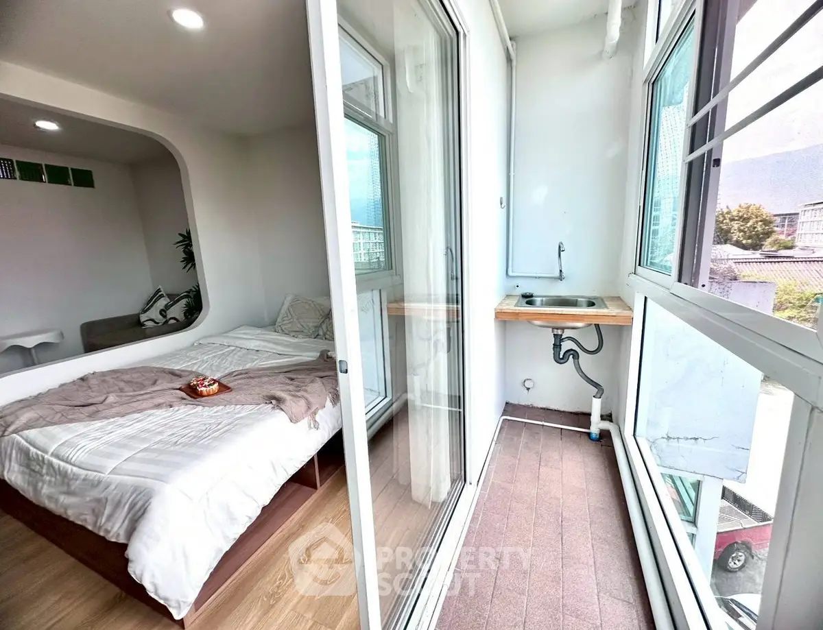 Modern bedroom with balcony and city view, featuring a cozy bed and sleek design.