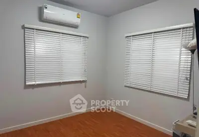 Minimalist room with wooden flooring and air conditioning, featuring white blinds on windows.