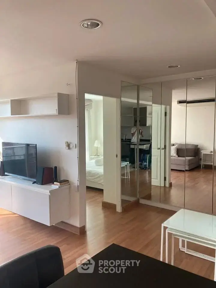 Modern open-plan living room with mirrored closet and wooden flooring