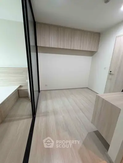 Modern minimalist bedroom with wooden flooring and built-in storage cabinets