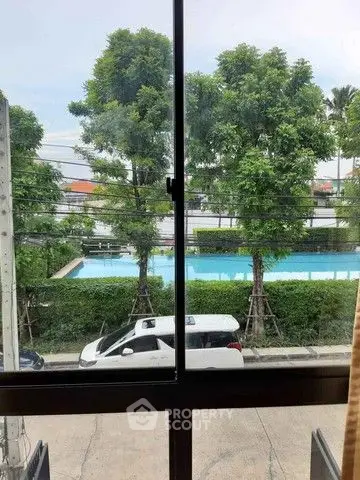 Scenic view from window overlooking pool and lush greenery.