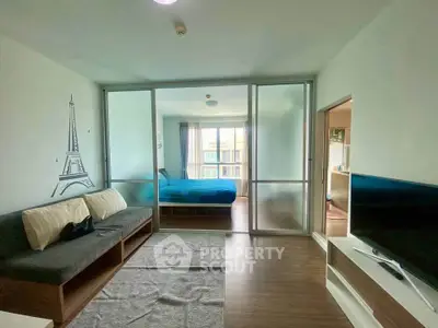 Modern living room with sliding glass doors leading to a cozy bedroom, featuring stylish decor and ample natural light.
