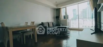Spacious living room with modern furniture and city view balcony in high-rise apartment.