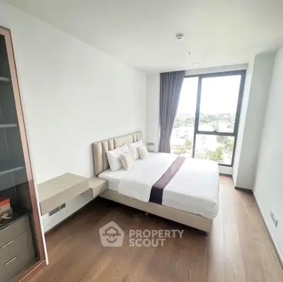 Spacious bedroom with large window offering a stunning view, featuring modern decor and wooden flooring.