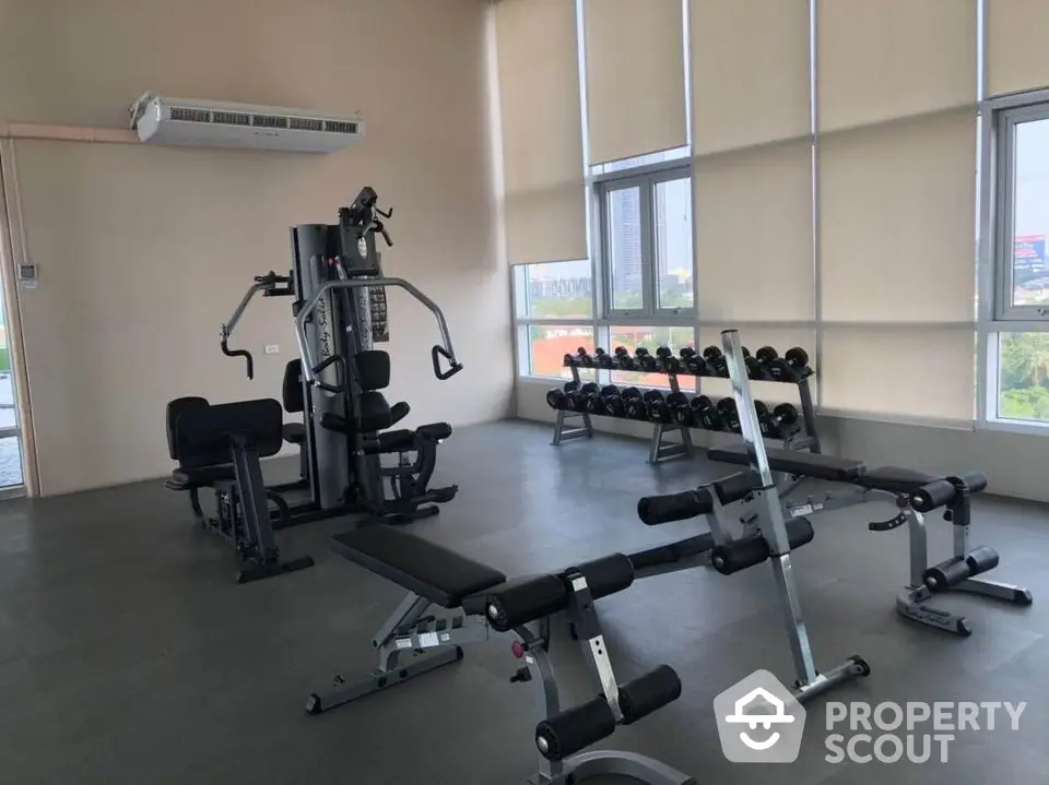 Spacious modern gym with state-of-the-art equipment and large windows offering city views.