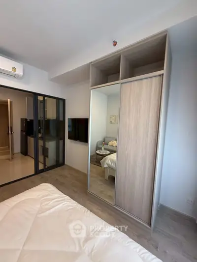 Modern bedroom with mirrored wardrobe and cozy bed in stylish apartment.