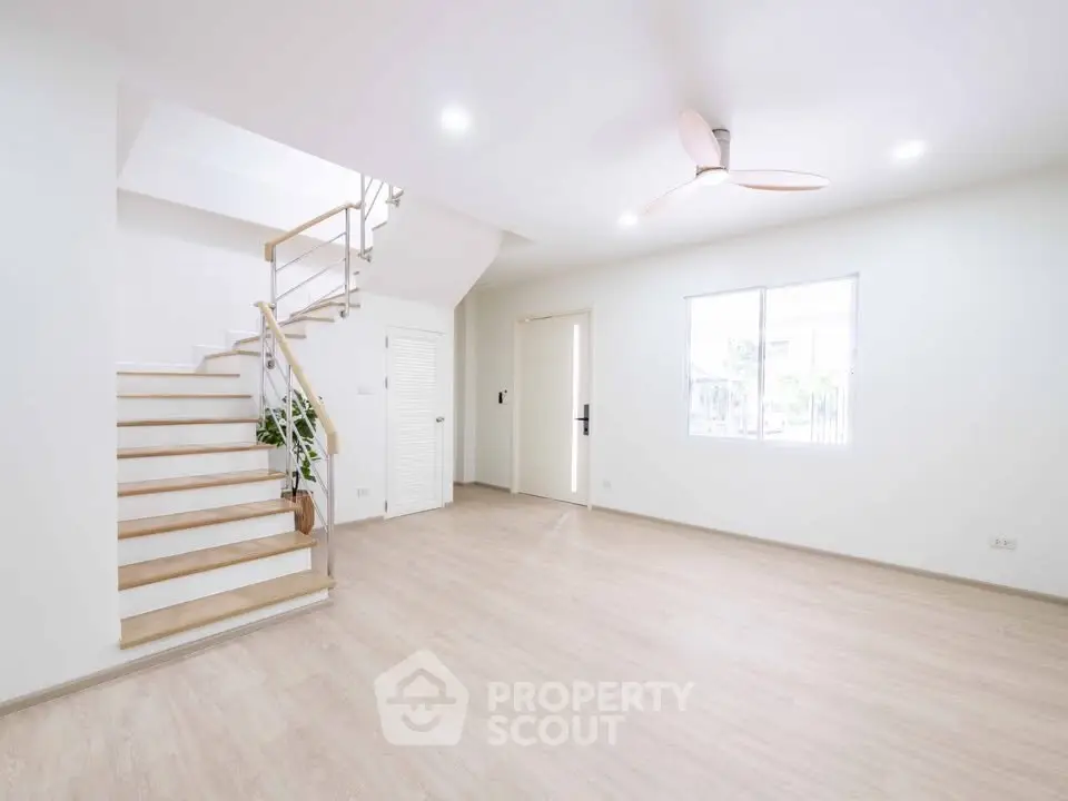 Spacious modern living room with wooden flooring and staircase, perfect for family gatherings.