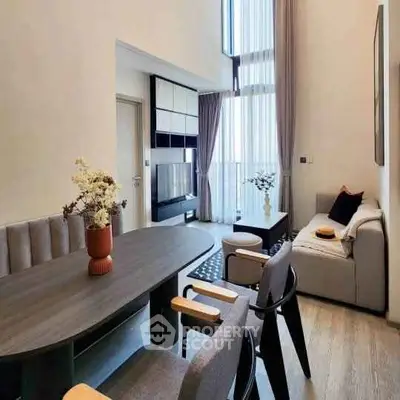 Modern living room with high ceilings and elegant decor, featuring a cozy sofa and stylish dining area.