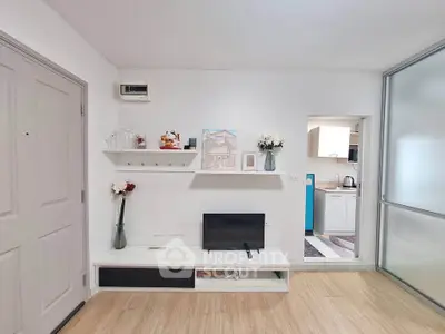 Modern living room with sleek TV unit and open kitchen view, showcasing minimalist design and bright ambiance.