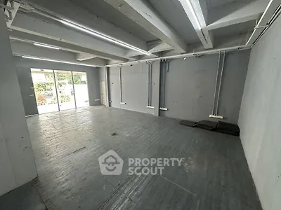 Spacious industrial-style room with large windows and exposed beams