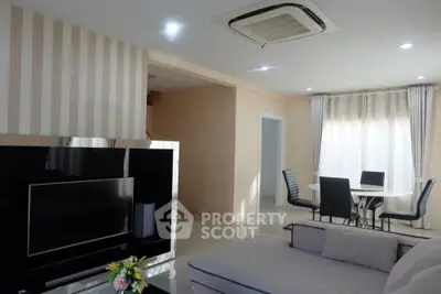 Spacious and well-lit living room with modern furnishings, large TV, and elegant dining area, perfect for entertaining and relaxation.