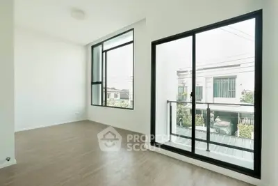 Bright and spacious room with large windows and modern flooring, offering a serene view of the neighborhood.
