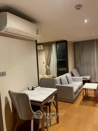 Modern living room with cozy seating and dining area, featuring elegant decor and natural lighting.