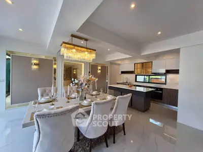 Luxurious open-plan dining and kitchen area with elegant chandelier and modern decor.