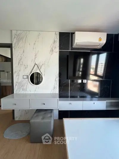 Modern living room with sleek black and white decor, featuring a wall-mounted TV and stylish air conditioning unit.
